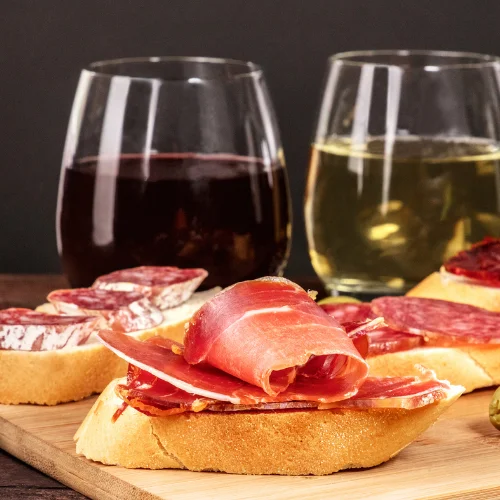 cured meat taps with 2 glasses of wine sitting on a table